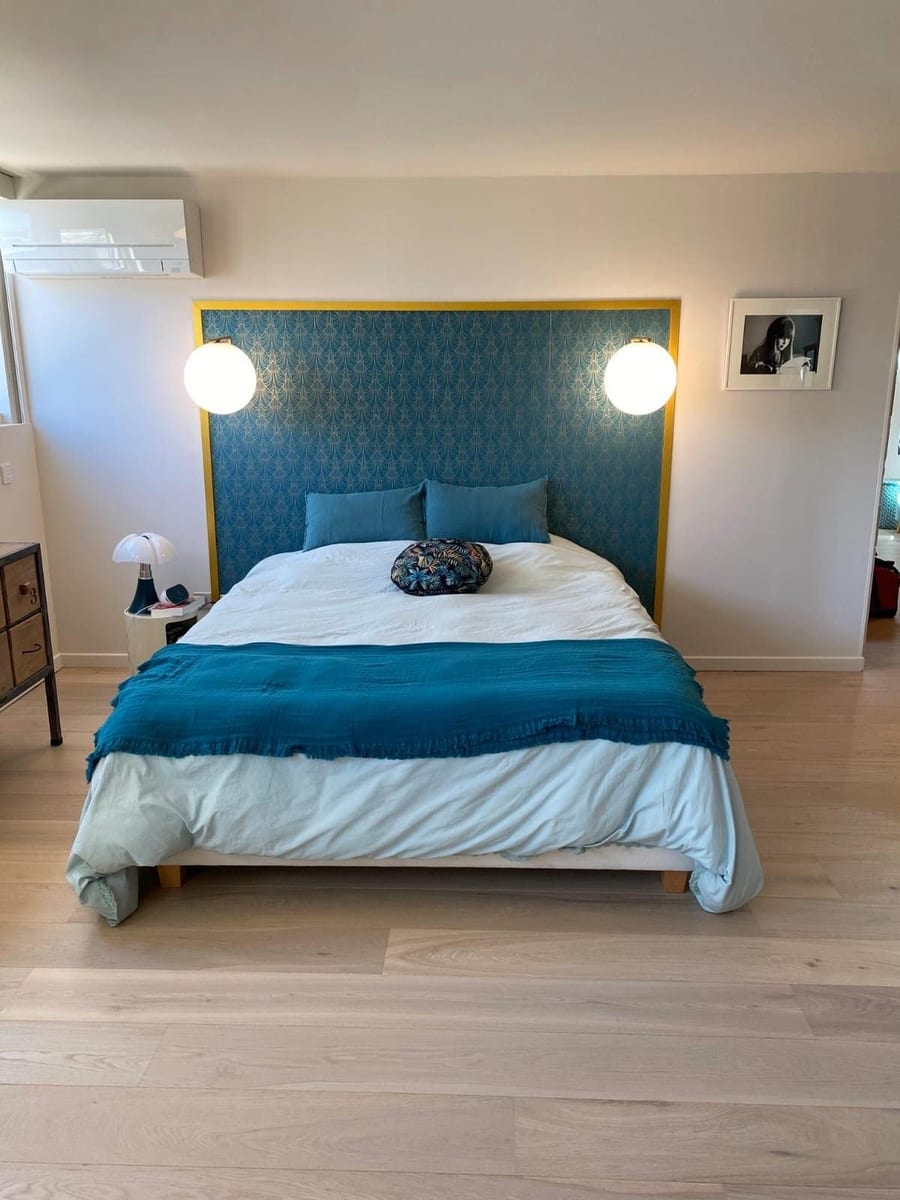 Chambre rénovée avec tête de lit tapissée et parquet chêne clair